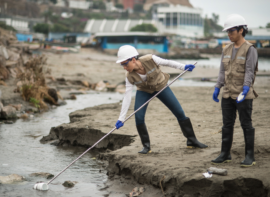 Estudiantes de Ingeniería Ambiental realizando muestreo de agua en campo, analizando la calidad de un río costero con equipo de protección y herramientas especializadas.